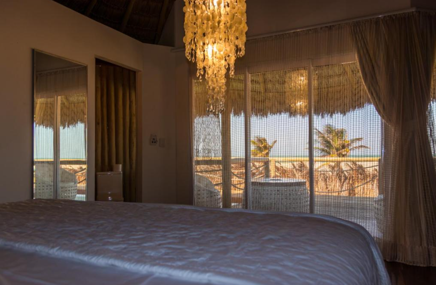 Vista da cama para os coqueiros e o mar através da janela
